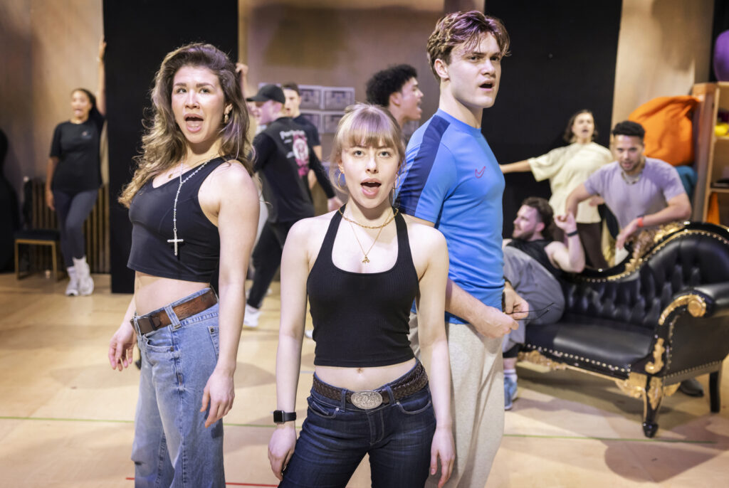 Nic Myers (Kathryn), Abbie Budden (Annette) and Will Callan (Sebastian) rehearsing with the 2025 touring cast - Pamela Raith Full cast ensemble of Cruel Intentions: The '90s Musical UK and Ireland tour practicing choreography, set against a vibrant stage backdrop.