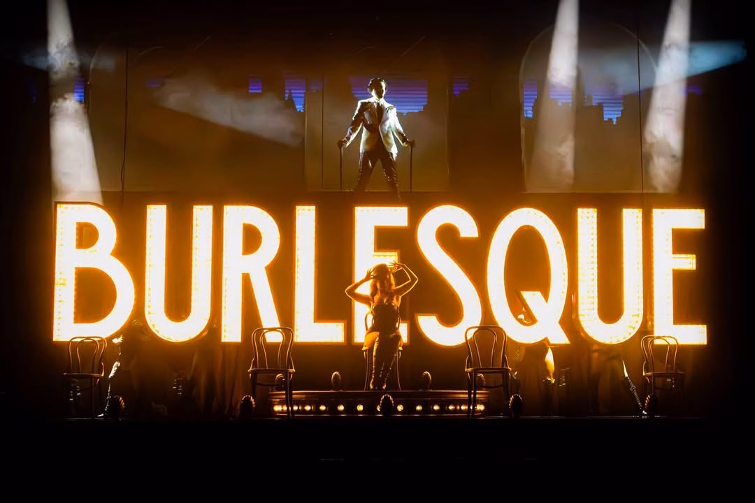 Burlesque The Musical UK Tour performers on stage in front of the large illuminated Burlesque sign