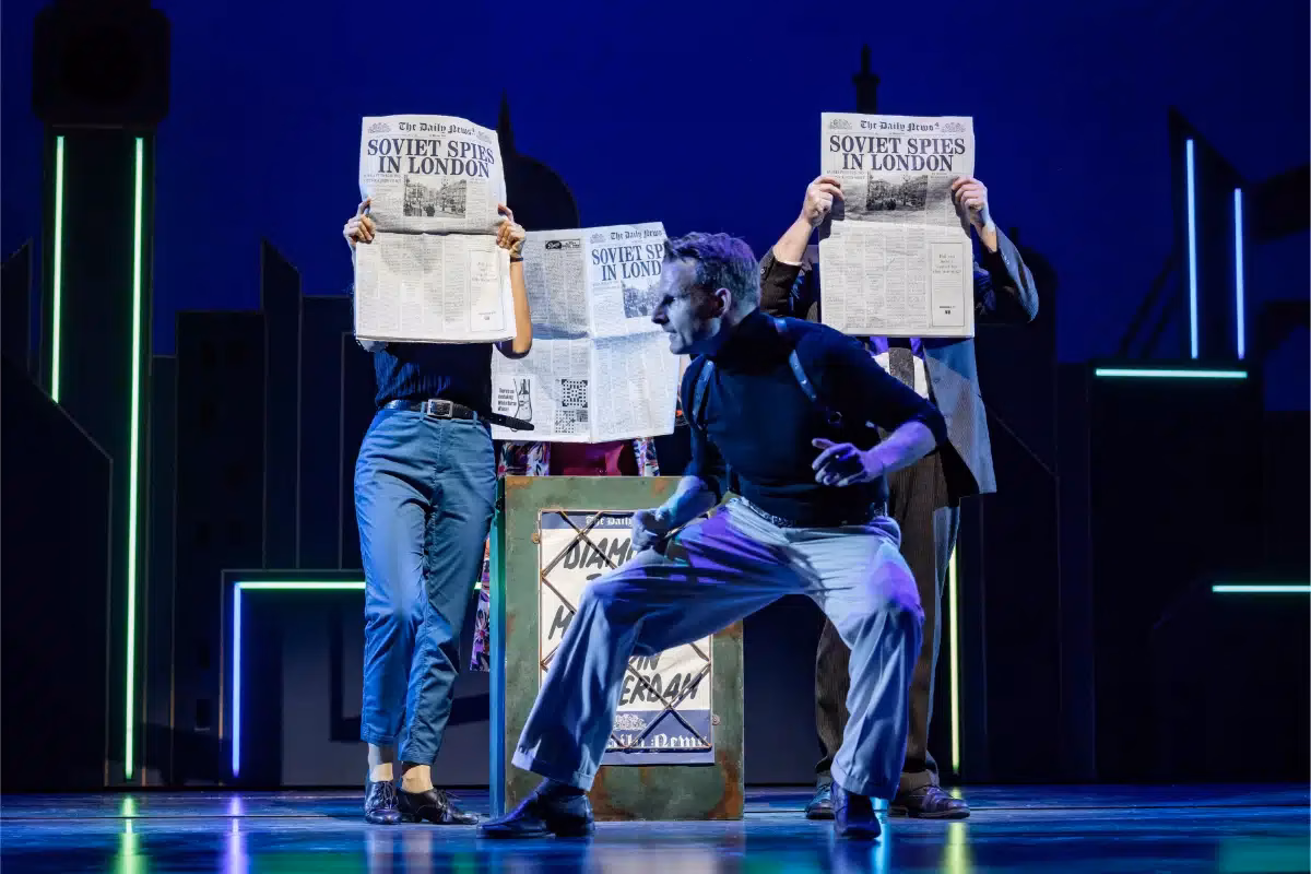 The Comedy About Spies cast holding newspapers during a spy scene at the Adelphi Theatre