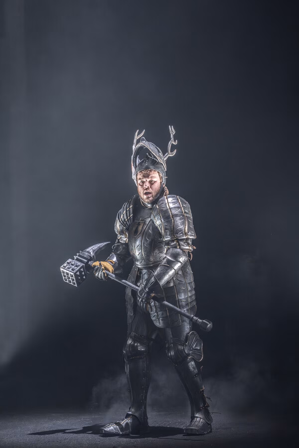 Armoured performer standing in dramatic stage lighting