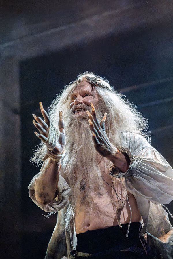White-haired character in dramatic costume on stage