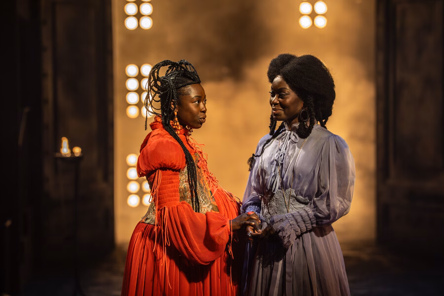 Two characters in conversation under warm stage lighting